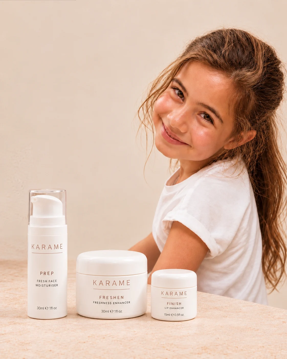 A young girl smiling beside the three KARAME products on a sunlit table